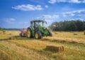 green tractor on brown grass field under blue sky during daytime