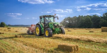 green tractor on brown grass field under blue sky during daytime