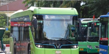 A bright green electric bus parked at a station.