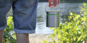 person in blue denim jeans holding stainless steel bucket