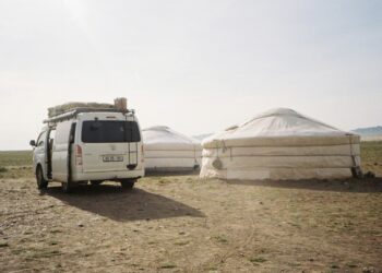 White van parked near yurts on a sunny day