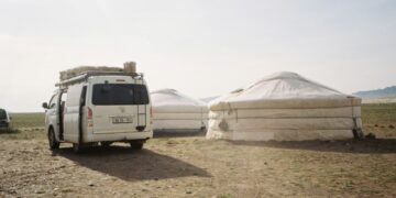 White van parked near yurts on a sunny day