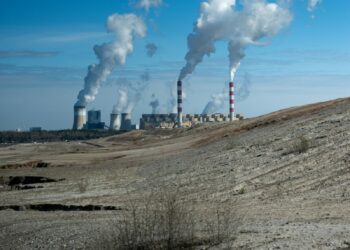 Industrial power plant with smoke stacks under blue sky.
