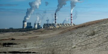 Industrial power plant with smoke stacks under blue sky.