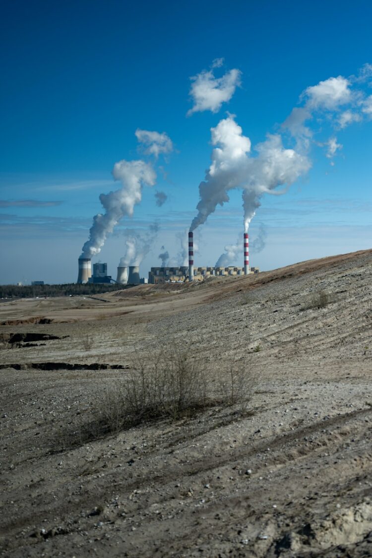 Industrial power plant with smoke stacks under blue sky.