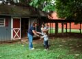 Family interacts with a woman near a shed.