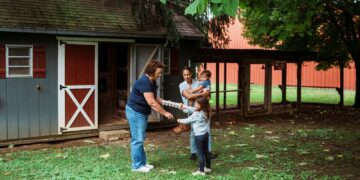 Family interacts with a woman near a shed.