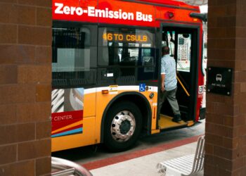 Man boarding a zero-emission bus at a station.