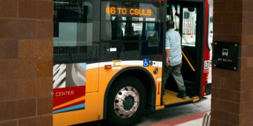 Man boarding a zero-emission bus at a station.