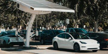 Electric car parked at a solar charging station outdoors, highlighting renewable energy and innovation.