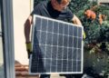 A worker installs a solar panel on a roof, promoting clean and renewable energy.