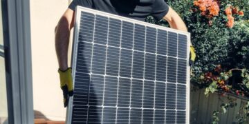 A worker installs a solar panel on a roof, promoting clean and renewable energy.
