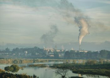 A factory emitting smoke over a natural landscape in Kon Tum, Vietnam.