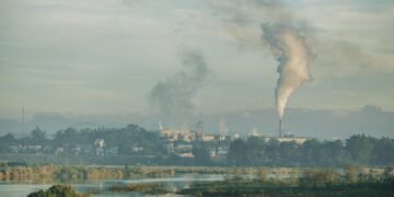 A factory emitting smoke over a natural landscape in Kon Tum, Vietnam.