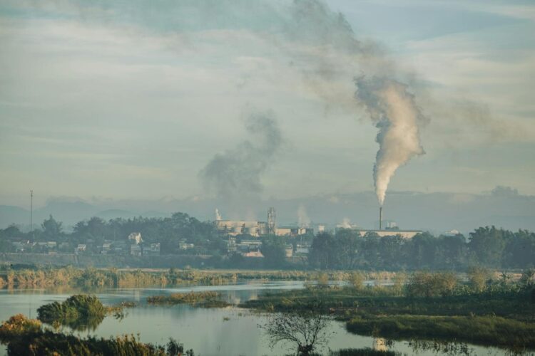 A factory emitting smoke over a natural landscape in Kon Tum, Vietnam.