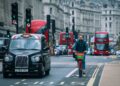 A cyclist riding amidst traffic in London's bustling streets.