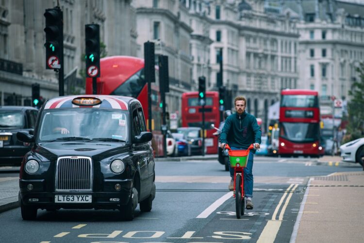 A cyclist riding amidst traffic in London's bustling streets.