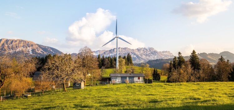 Wind turbine amidst lush country landscape with mountains. A serene depiction of renewable energy in nature.